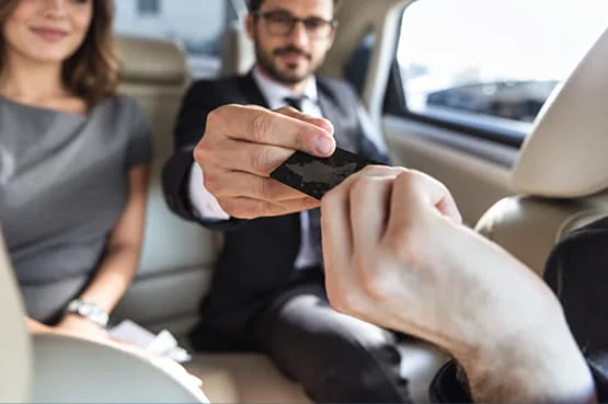 Chauffeur de taxi remettant un terminal de paiement bancaire à un passager dans le véhicule.